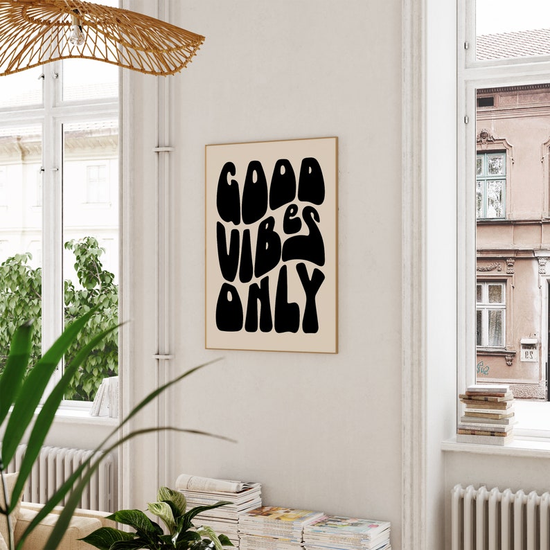 May include: A black and white print with the text "GOOD VIBES ONLY" in a retro, psychedelic font style. The print is framed and hanging on a white wall.