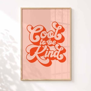 Puede incluir: Una l&aacute;mina de arte mural enmarcada con el texto Cool to be Kind en una fuente naranja llamativa y estilizada con una sombra paralela de color rosa suave. El texto est&aacute; centrado sobre un fondo rosa claro, dentro de un marco de madera clara.