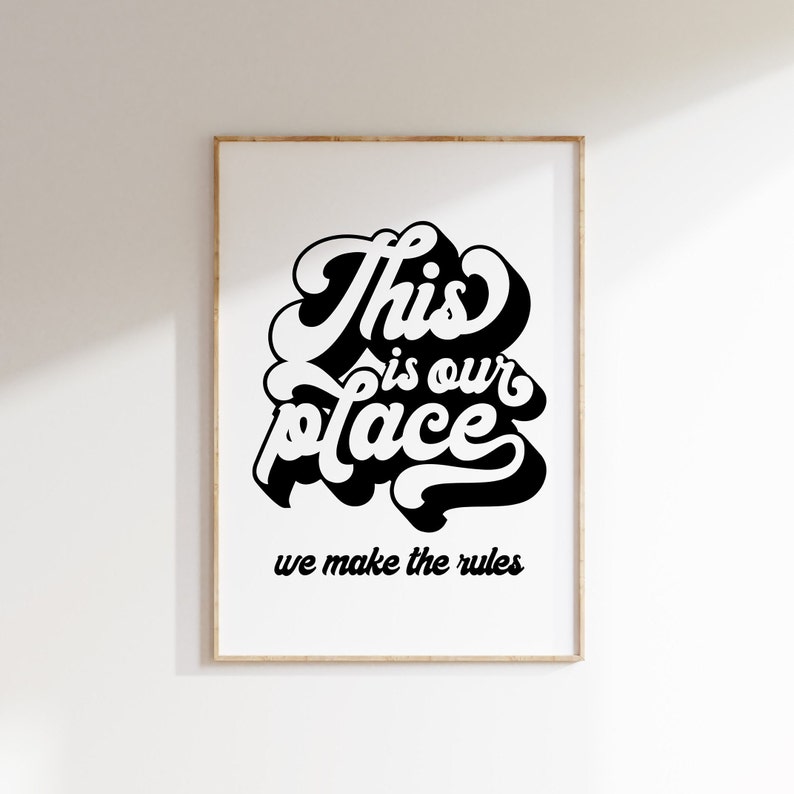 May include: Black and white typography print with the text "This is our place we make the rules" on a white background in a wooden frame.