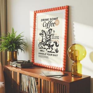 Cowgirl-inspired wall art print that says “Drink Some Coffee, Put Your Boots On, Handle Your Sh*t,” styled for a modern coffee bar or kitchen coffee station with a warm western vibe and motivational decor.