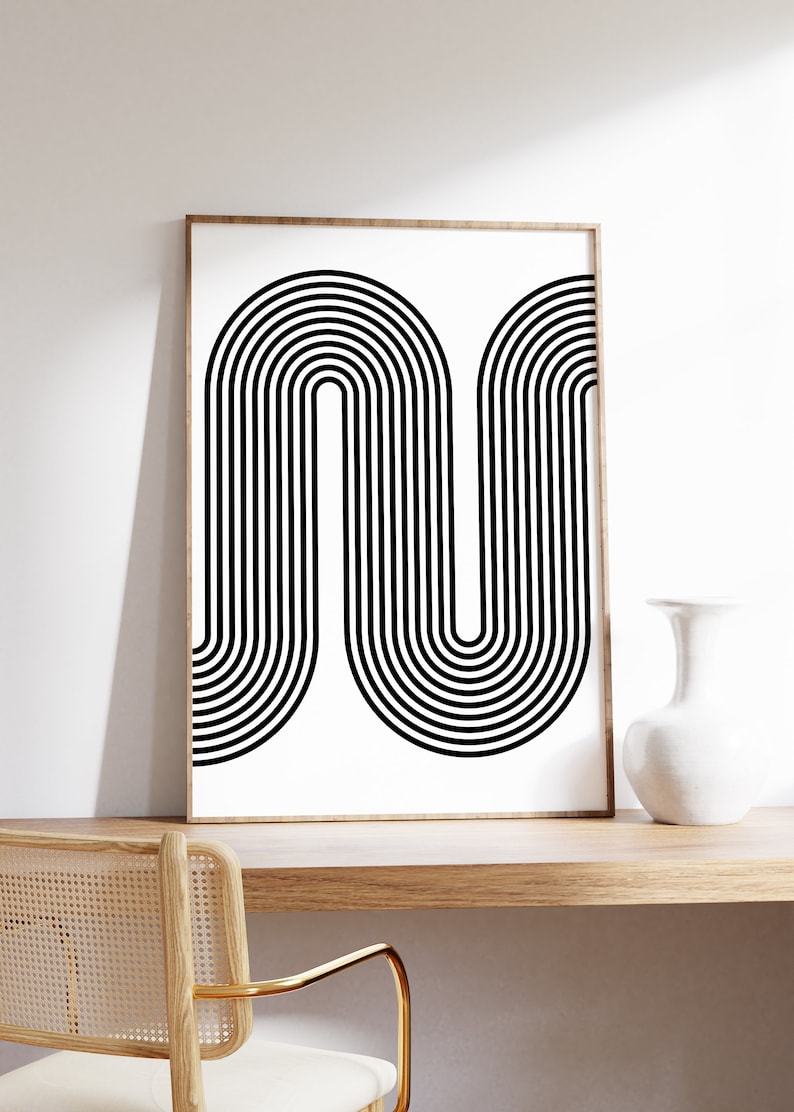 Puede incluir: Impresi&oacute;n de arte abstracto en blanco y negro con un dise&ntilde;o geom&eacute;trico de l&iacute;neas curvas. La impresi&oacute;n est&aacute; enmarcada en un marco de madera claro y est&aacute; colgada en una pared blanca.
