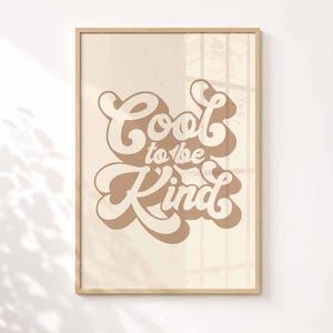 Puede incluir: Una l&aacute;mina de arte mural rectangular en un marco de madera clara con el texto Cool to be Kind en una fuente retro marr&oacute;n y negrita con un efecto de sombra paralela, sobre un fondo beige claro s&oacute;lido dentro del marco.