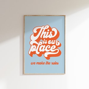 May include: A light blue poster with the text "This is our place we make the rules" in orange and white lettering. The text is in a retro, stylized font.