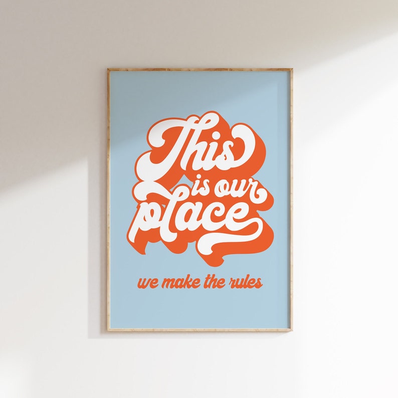 May include: A light blue poster with the text "This is our place we make the rules" in orange and white lettering. The text is in a retro, stylized font.