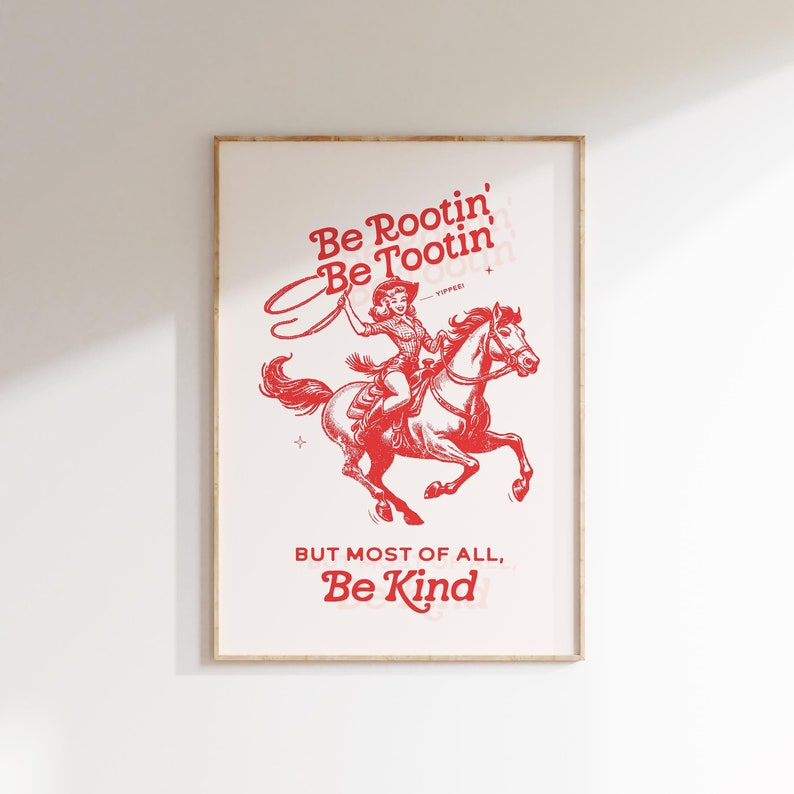 Pu&ograve; includere: Stampa rossa e bianca con una cowgirl a cavallo. Il testo recita "Be Rootin' Be Tootin'" e "But most of all, Be Kind".