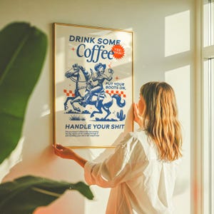 Cowgirl-inspired wall art print that says “Drink Some Coffee, Put Your Boots On, Handle Your Sh*t,” styled for a modern coffee bar or kitchen coffee station with a warm western vibe and motivational decor.