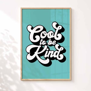 K&ouml;nnte beinhalten: Ein gerahmter Wandkunstdruck mit einem hellen t&uuml;rkisfarbenen Hintergrund und dem wei&szlig;en Text Cool to be Kind in einer fetten, abgerundeten Retro-Schriftart. Die Schrift hat einen dicken schwarzen Schlagschatten und der Druck ist in einem hellen Holzrahmen.