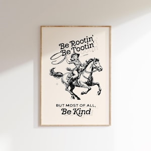 Pu&ograve; includere: Illustrazione in bianco e nero di una cowgirl a cavallo che tiene un lazo. Il testo recita "Be Rootin' Be Tootin' - YIPPEE! - BUT MOST OF ALL, Be Kind."