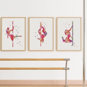 Peut inclure: Trois impressions encadrées à l'aquarelle représentant des danseuses de pole dance dans différentes poses. Chaque impression présente une danseuse dans des tons de rose, de violet et d'orange, avec une barre rouge ou verte. L'œuvre est sur fond blanc.
