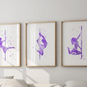 Könnte beinhalten: Set aus drei gerahmten Kunstdrucken mit Aquarellillustrationen von Poledance-Tänzerinnen in verschiedenen Posen. Die Kunstwerke in Lila mit Spritzeffekt sind vor weißem Hintergrund in hellen Holzrahmen gefasst.