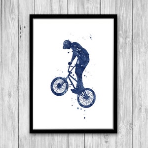 Puede incluir: Una silueta azul en acuarela de una persona realizando una acrobacia en una bicicleta BMX. La bicicleta est&aacute; en el aire con la rueda delantera levantada. La imagen tiene un fondo blanco.