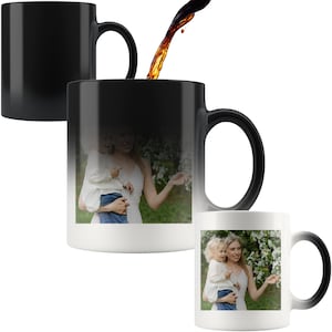 May include: A black magic mug with a photo of a mother and child in a garden. The mug changes color when hot liquid is added, revealing the photo.