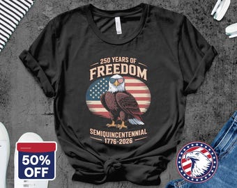 May include: Black t-shirt featuring a patriotic design. The graphic includes an eagle wearing sunglasses with the American flag design, set against a backdrop of the American flag. Text reads "250 Years of Freedom" and "Semiquincentennial 1776-2026".