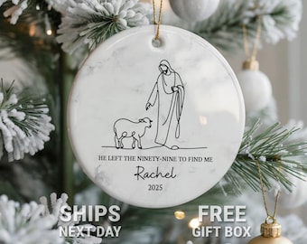 May include: White marble-effect Christmas ornament with a black line drawing of a figure and a lamb. Text includes "HE LEFT THE NINETY-NINE TO FIND ME", "Rachel", and "2025". The ornament hangs from a gold string.