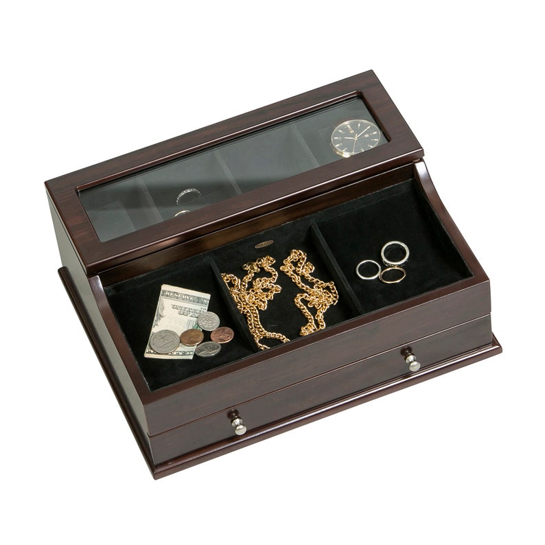 May include: A dark brown wooden jewelry box with a glass top and black velvet lining. The box contains a gold necklace, rings, a watch, and some money. The box has two small drawers with silver knobs.