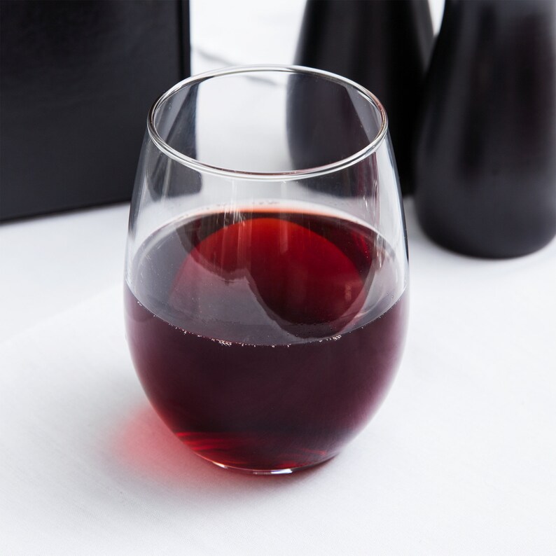 May include: A clear glass wine glass filled with red wine. The glass has a rounded bottom and a wide bowl.