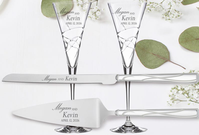 May include: A wedding cake cutting set with two champagne flutes and a cake knife. The flutes and knife are engraved with the names "Megan and Kevin" and the date "April 12, 2026".