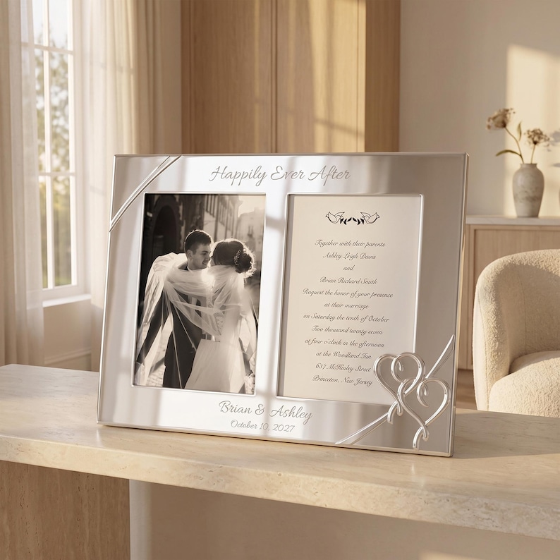 May include: A silver-toned double photo frame featuring the engraved text Happily Ever After at the top and Brian & Ashley October 10, 2027 at the bottom. The frame holds a black and white wedding photograph and a printed wedding invitation.