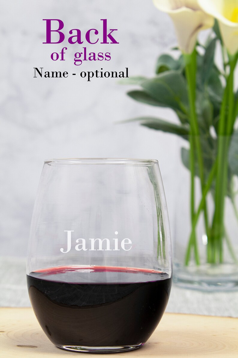 May include: A clear glass wine glass with the name "Jamie" etched on the side. The glass is filled with red wine.