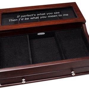 May include: A wooden jewelry box with a dark cherry finish. The box has a glass top with the inscription "If perfect's what you see Then I'd be what you mean to me." The interior is lined with black velvet and has multiple compartments and a drawer.