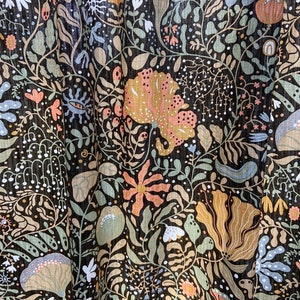 May include: A black fabric with a repeating pattern of stylized flowers, leaves, and vines in shades of green, brown, orange, and blue.