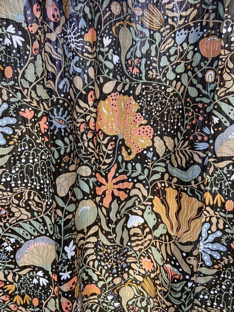 May include: A black fabric with a repeating pattern of stylized flowers, leaves, and vines in shades of green, brown, orange, and blue.
