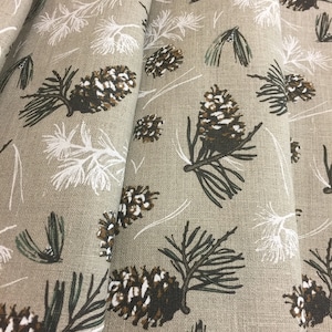 May include: Beige fabric with a repeating pattern of brown pine cones and green pine branches. The fabric has a subtle linen texture.