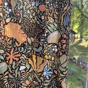 May include: Black fabric with a floral pattern in shades of orange, yellow, green, and blue. The fabric has a textured, linen-like appearance.