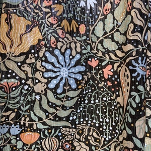 May include: A black fabric with a colorful floral pattern. The pattern features flowers, leaves, and other botanical elements in shades of blue, green, pink, and brown.