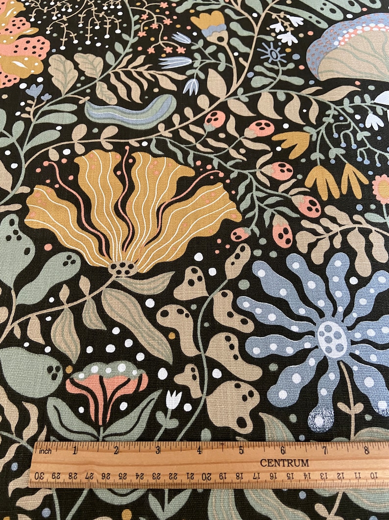 May include: Black fabric with a repeating pattern of stylized flowers, leaves, and mushrooms in shades of brown, beige, pink, blue, and white.