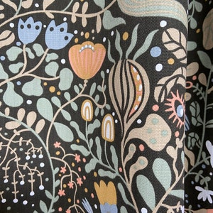 May include: Black fabric with a repeating pattern of stylized flowers, leaves, and geometric shapes in shades of blue, green, pink, and yellow.