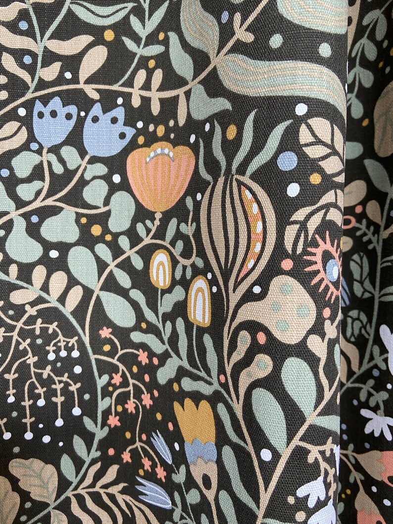 May include: Black fabric with a repeating pattern of stylized flowers, leaves, and geometric shapes in shades of blue, green, pink, and yellow.