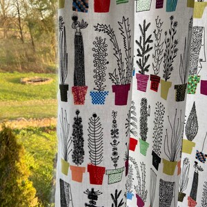 K&ouml;nnte beinhalten: Wei&szlig;er Stoff mit einem sich wiederholenden Muster aus schwarzen Linienzeichnungen von Topfpflanzen. Die Pflanzen sind in verschiedenen Formen und Gr&ouml;&szlig;en, und die T&ouml;pfe sind in verschiedenen Farben, darunter Rot, Gr&uuml;n, Blau und Gelb.