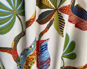 Peut inclure: Tissu blanc avec un motif floral coloré. Le motif présente des feuilles stylisées dans des tons de vert, rouge, bleu, jaune et marron. Les feuilles sont disposées en un motif répétitif.