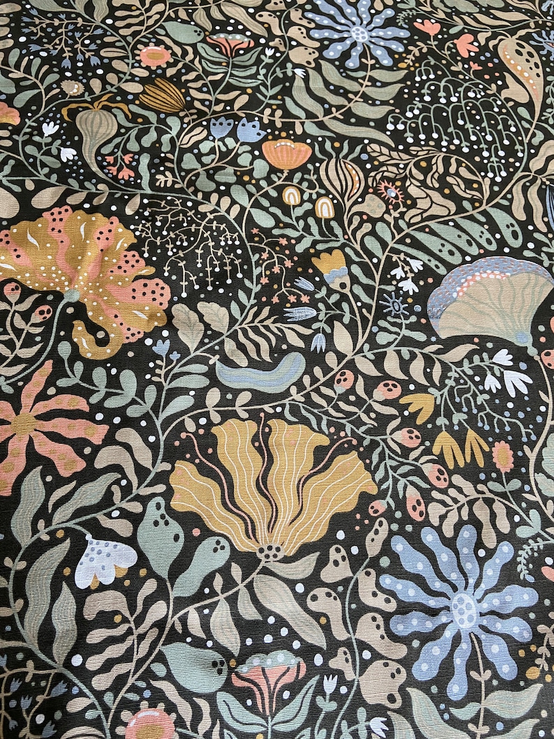 May include: A black fabric with a floral pattern. The flowers are in shades of pink, blue, yellow, and green. The background is a dark black.