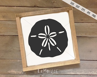 May include: A framed sign featuring a black sand dollar design on a white background. The sign is encased in a light brown wooden frame. The top right corner of the sign has the text "SVG . DXF . EPS . JPG . PNG". The bottom left corner of the sign has the text "LEMONADE DESIGN CO."