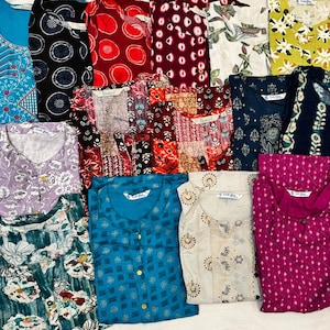 May include: A collection of folded, patterned tops in various colors, including blue, red, and green. The tops feature diverse designs, such as floral prints and geometric patterns. Each top has a V-neck and is neatly folded.