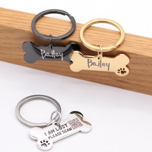 May include: Three dog bone-shaped keychains. One is black with the name "Bailey" engraved on it. Another is gold with the name "Bailey" and a paw print engraved on it. The third is silver with the text "I am lost please scan" and a paw print engraved on it.