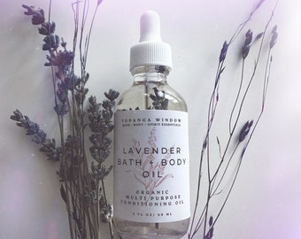 Peut inclure: Une bouteille en verre transparent avec un compte-gouttes blanc et une étiquette blanche. L'étiquette indique "Topanga Window Mind Body Spirit Essentials Lavender Bath + Body Oil Organic Multi Purpose Conditioning Oil 2 FL OZ/60 ML". La bouteille est entourée de brins de lavande séchés.