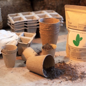 Puede incluir: Una bolsa de sustrato de turba para sembrar y plantar, etiquetada con "Peat Substrate" y "Nature for the creator". La bolsa está junto a una pila de macetas de papel marrón y un guante de jardinería blanco.