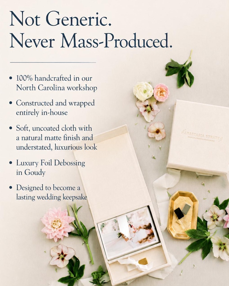 May include: A cream-coloured fabric-covered box with a lid, containing a photograph and a small gold object. The box features the text 'Not Generic. Never Mass-Produced.' and 'Anastasia Strates'. It is surrounded by pink and white flowers.