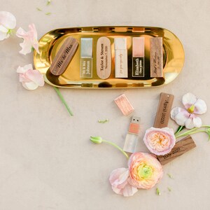 May include: A gold tray with wooden USB drives engraved with names and dates. The tray is surrounded by pink and peach flowers.