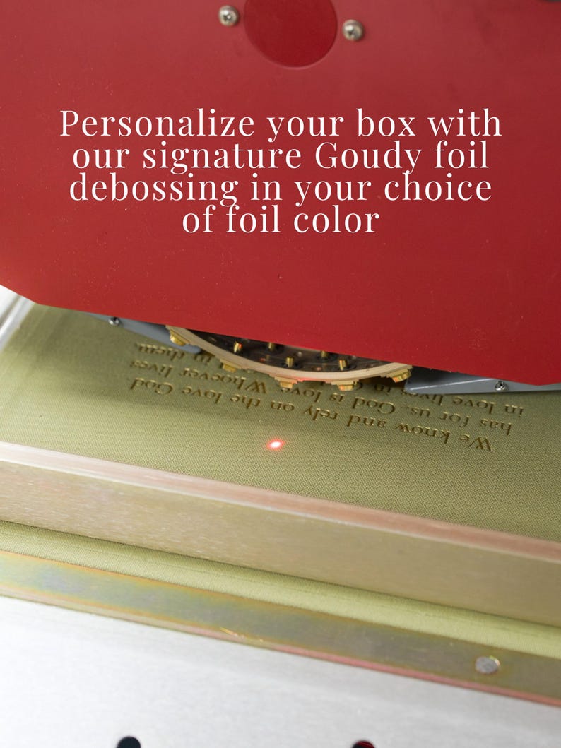 May include: A red foil stamping machine presses text onto a light green surface. The text reads: Personalize your box with our signature Goudy foil debossing in your choice of foil color. Below, the machine imprints: We know and rely on the love God has for us. God is love. Whoever lives in love lives in God.