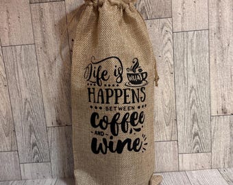 May include: A burlap wine bag with a black print that reads "Life is what happens between coffee and wine".