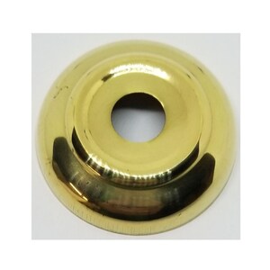 May include: A brass door knob escutcheon with a round, slightly raised center and a smooth, polished finish.