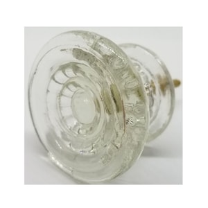 May include: Clear glass cabinet knob with a decorative, textured design. The knob has a brass screw.