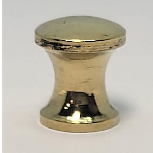 May include: A gold-colored cabinet knob with a rounded top and base, connected by a narrower, hourglass-shaped center. The knob has a shiny, reflective surface, suggesting a polished metal finish. The hardware is designed for furniture.