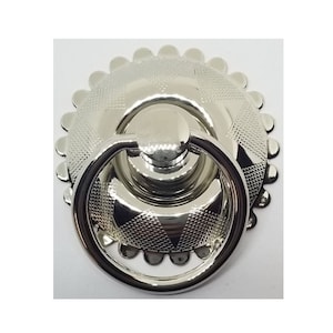 May include: A silver ring pull door handle with a decorative, scalloped edge.