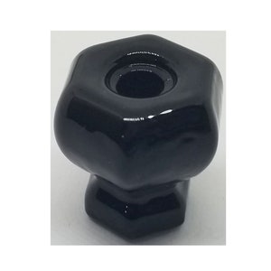 May include: Black ceramic knob with a hexagonal shape and a round hole in the center.