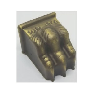 May include: A gold-toned metal furniture leg with a claw design. The leg has a detailed design and a brushed finish.